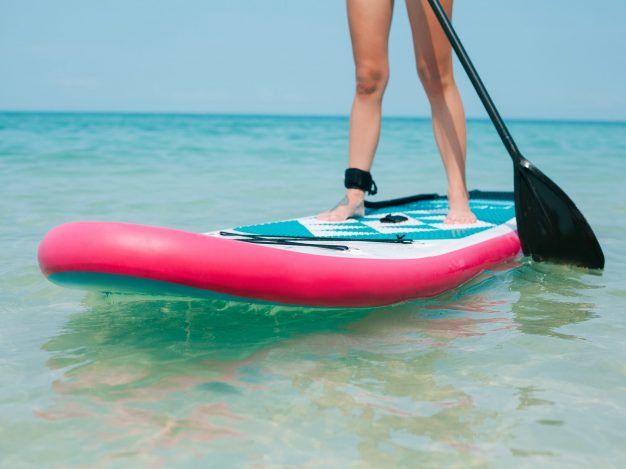 cropped view of woman on stand up paddle board on sea